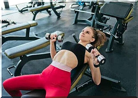 A woman lifting weights at the gym.