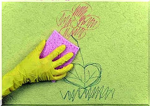 A person using a sponge to clean a drawing of a wall.