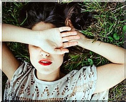 woman lying on the grass with her hand in front of her eyes