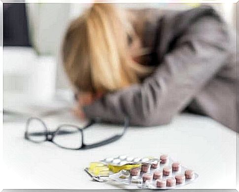 A woman with a headache is lying with her head on the table