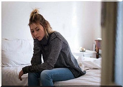 A woman with a headache sitting on the bed