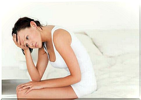 Woman in white sitting in bed treating urinary tract infections early to avoid complications.